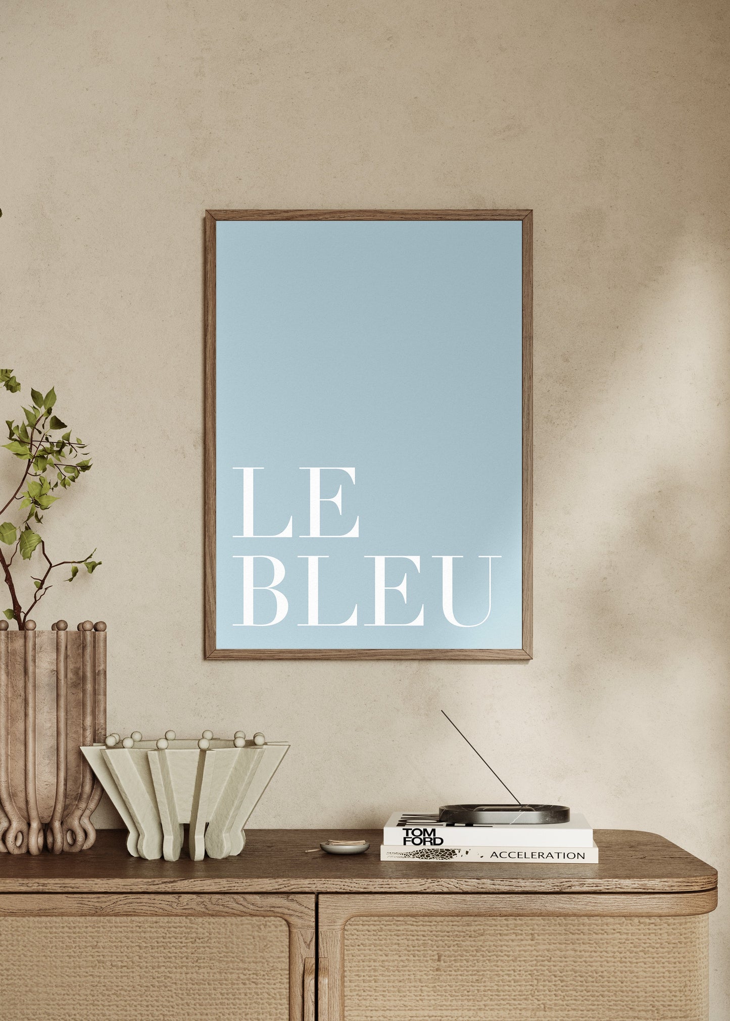 Framed artwork with 'LE BLEU' text on a wall above a wooden console table.